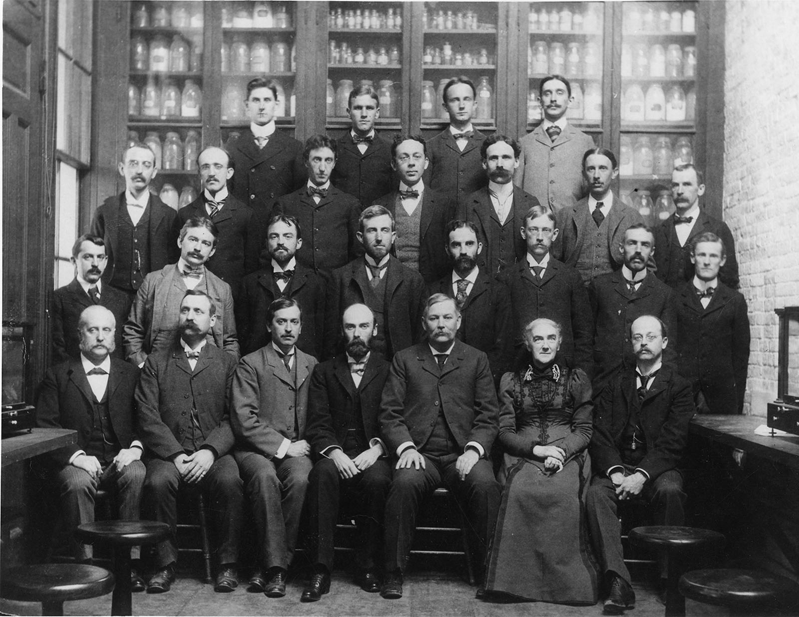 Ellen Swallow Richards and the staff of the Massachusetts Institute of Technology’s Chemistry Department. Richards is the only woman in the photo. There are 25 men. All of the people photographed are white. Richards is seated in the first of four rows, and is the second figure from the right. 