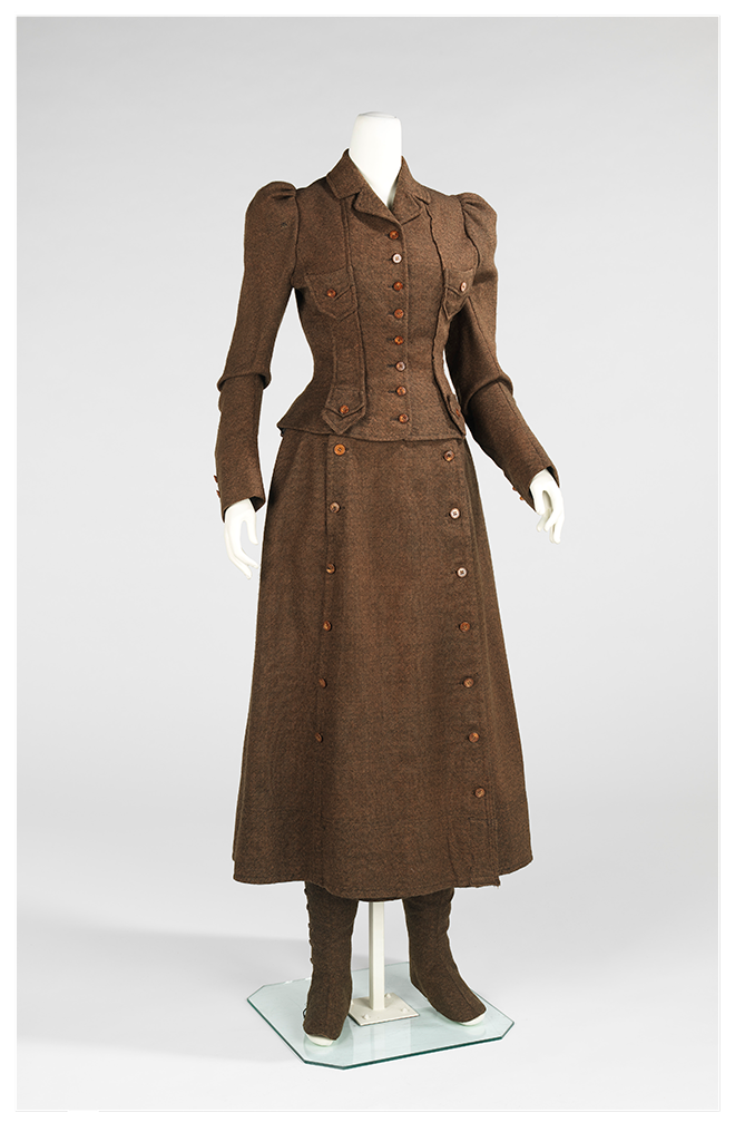 A women’s brown cycling suit from the 1890s with a bifurcated skirt. The wide shorts have been made to look like a skirt with a buttoned-down cloth to cover the opening of the legs. The jacket covers the arms and chest, with additional buttons.