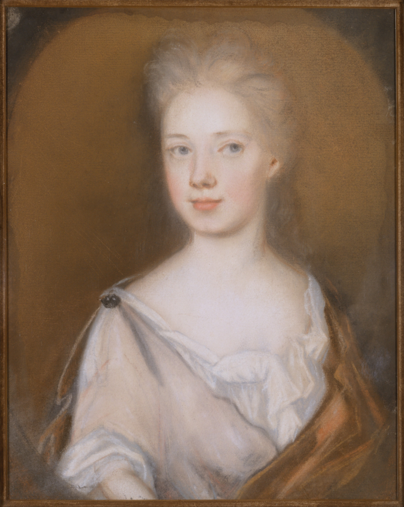 Pastel and red chalk portrait of a white female wearing a white chemise with a lower neckline, pinned at the shoulder, draped in a brown cloak set on a light brown background. 