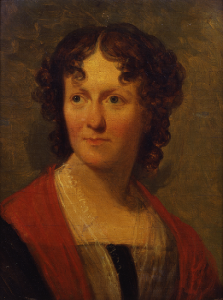 An 1824 oil portrait painting of a young woman with curly brown hair, Frances Wright, wearing a white lace fichu below a black and red bordered top. Dimensions: 16 ⅝ x 12 ¾.” 