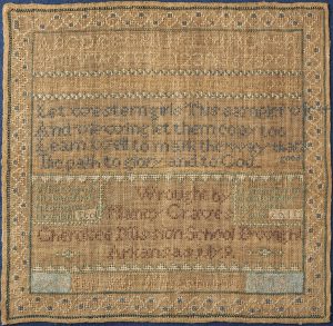 Yellow and very faded 1828 linen sampler by Nancy Graves of the Cherokee Mission School in Arkansas. Decorative border surrounds alphabet lettering and biblical text embroidered through silk crewels. Dimensions: 14”x14.”